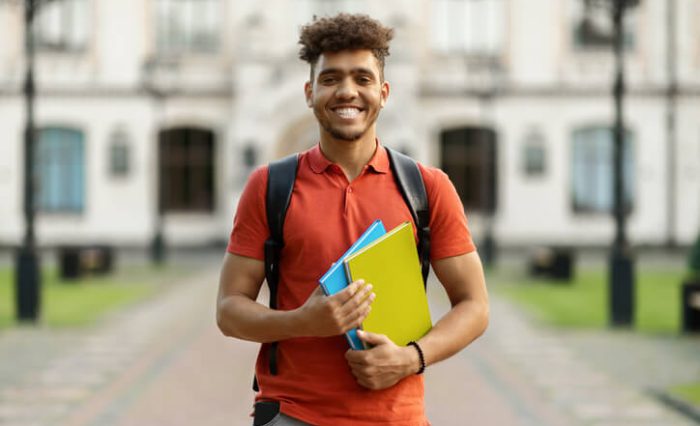 An international student holding books outside of an ESL school